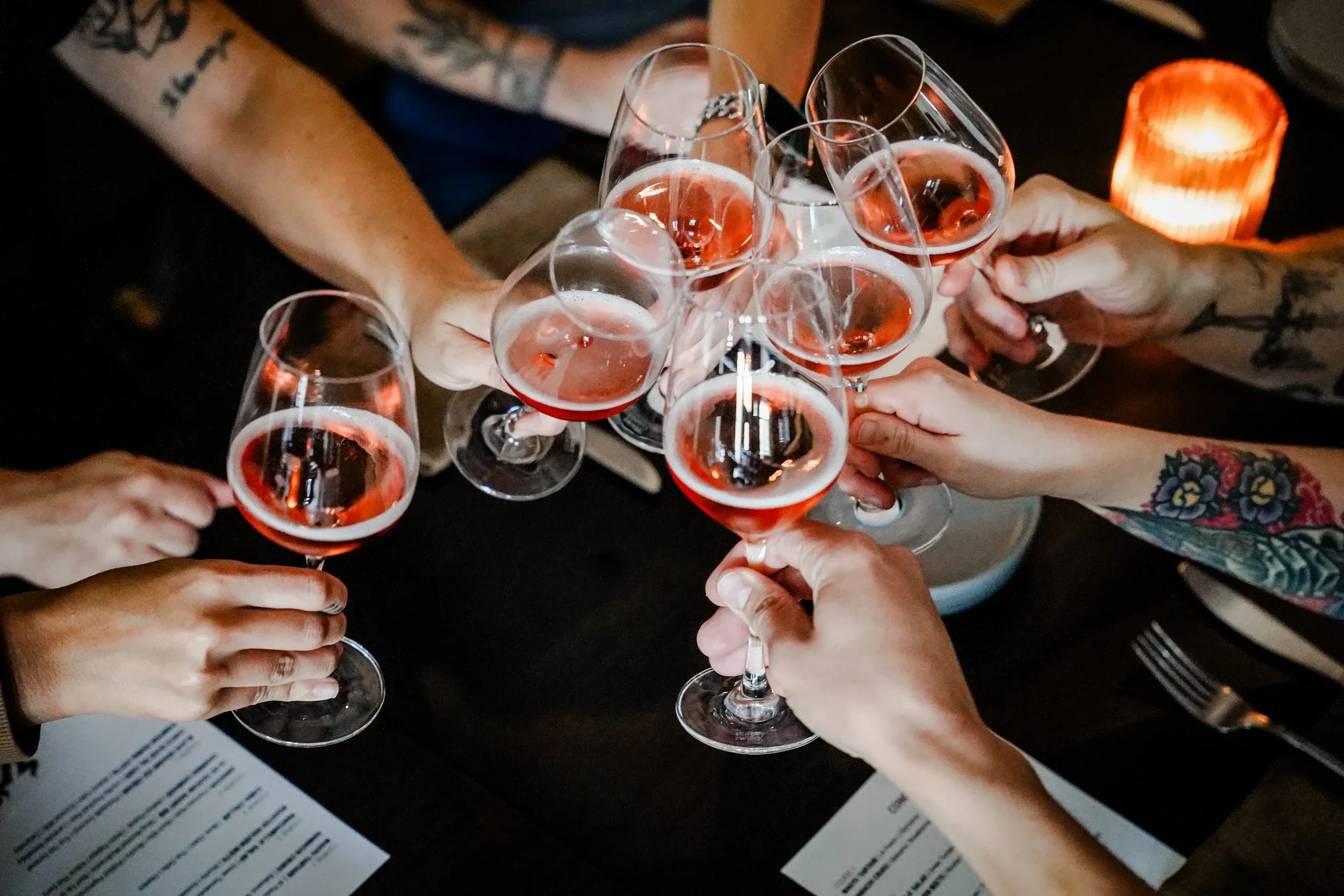 Guests raising glasses of rosé over a candlelit table