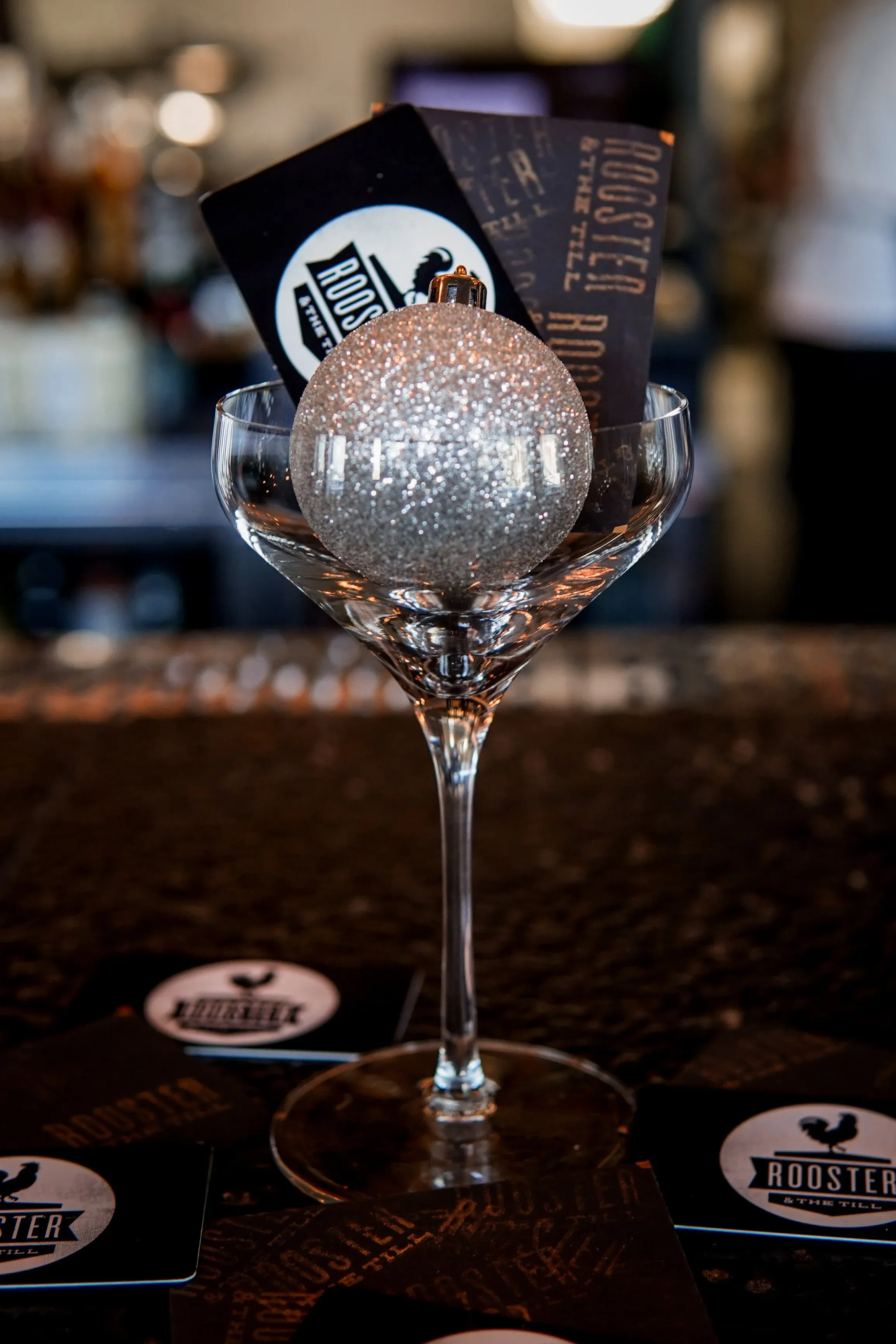 Rooster & the Till gift cards tucked in a coupe glass with a silver ornament